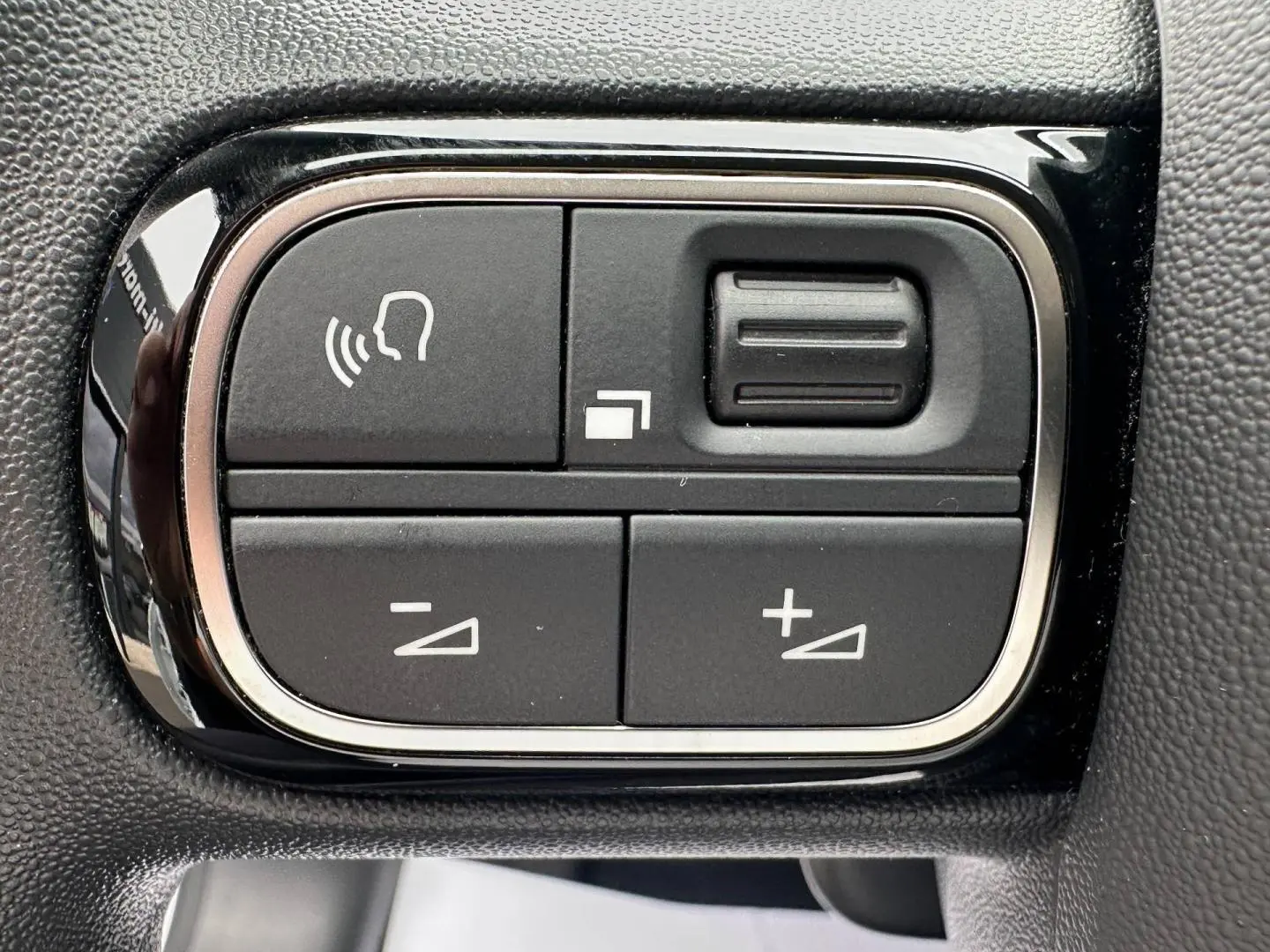 Gros plan sur les commandes du volant noir de la Citroën C3 blanche Banquise, boutons de réglage audio et vocal.