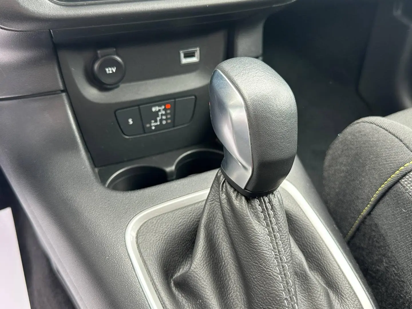 Gros plan sur le pommeau de levier de vitesse cuir noir et console centrale grise de la Citroën C3 2023.