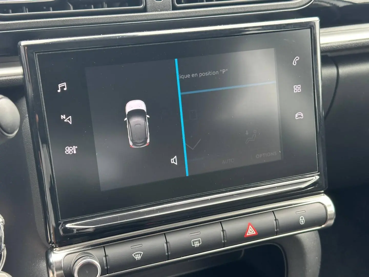 Vue rapprochée de l'écran tactile central et des commandes de la Citroën C3 blanche, affichant l'aide au stationnement.