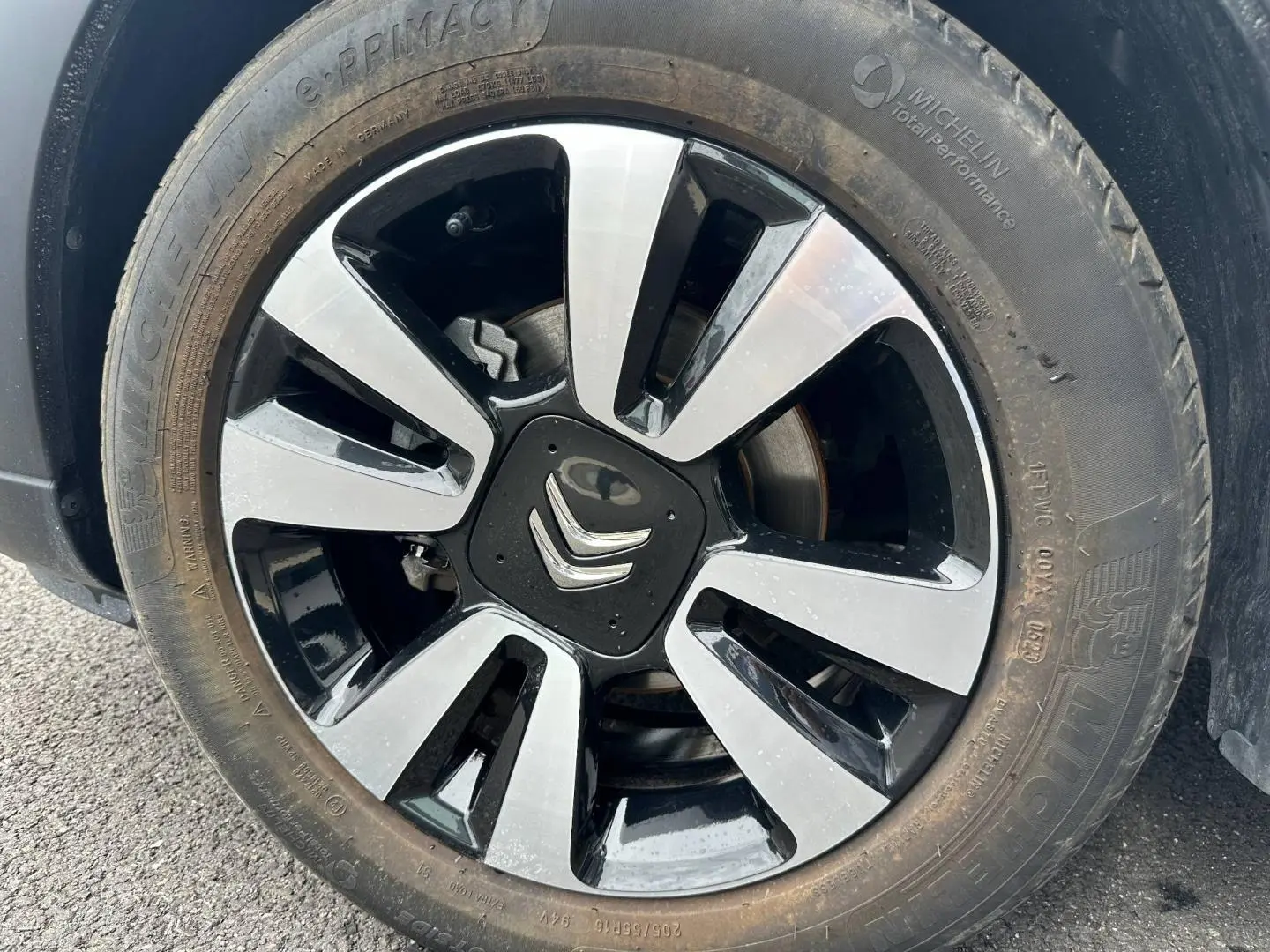 Gros plan sur la jante alu bicolore noire et argentée d'une Citroën C3 Blanc Banquise, avec logo Citroën central visible.