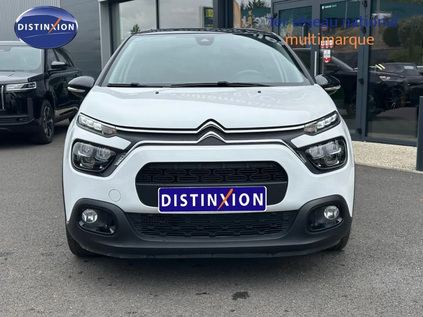 Vue avant d'une Citroën C3 blanche Banquise avec calandre noire et phares LED distinctifs sur un parking.
