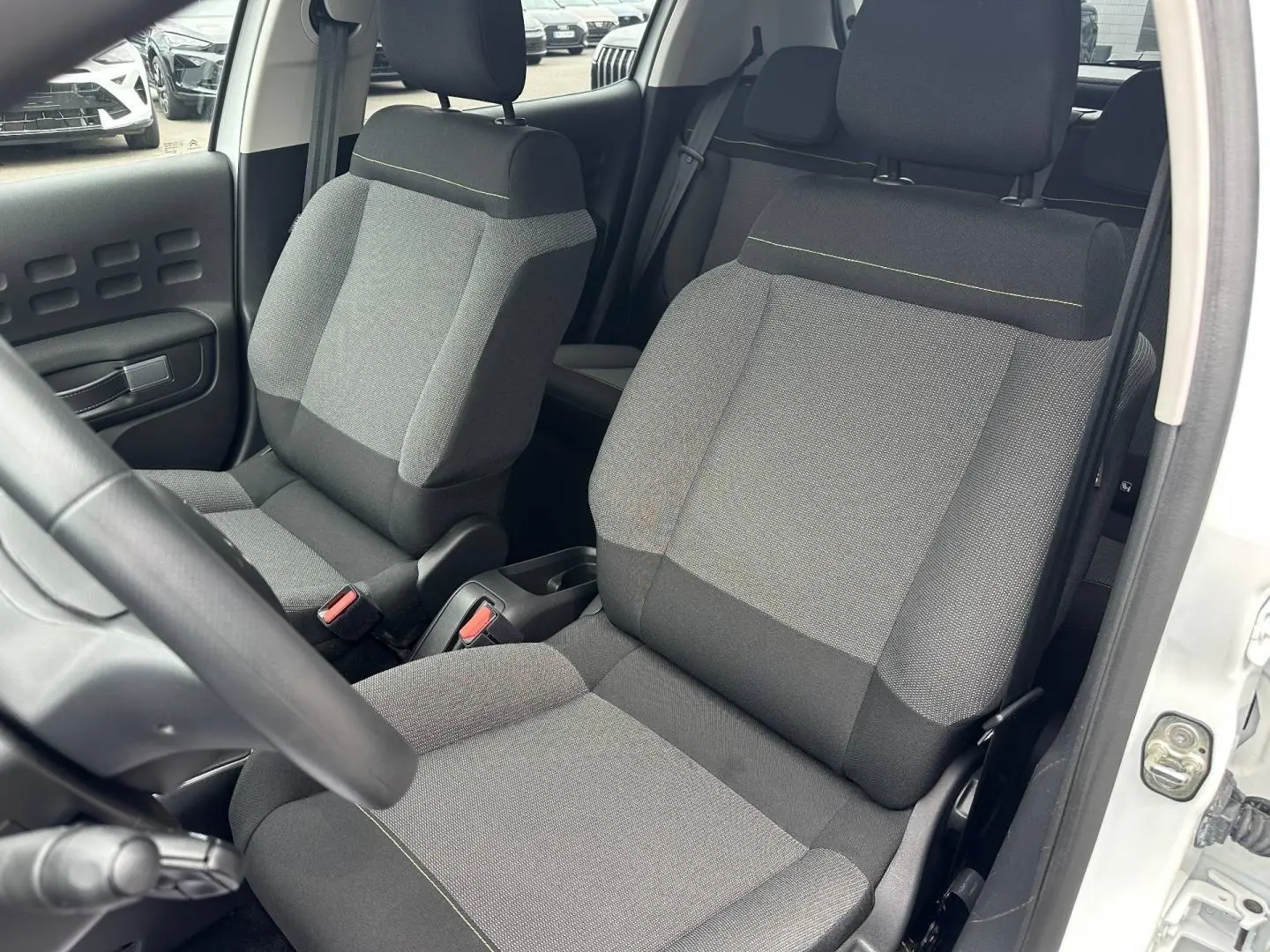 Vue intérieure sur les sièges avant gris tissu Mica Grey d'une Citroën C3 Blanc Banquise, porte ouverte côté droit.