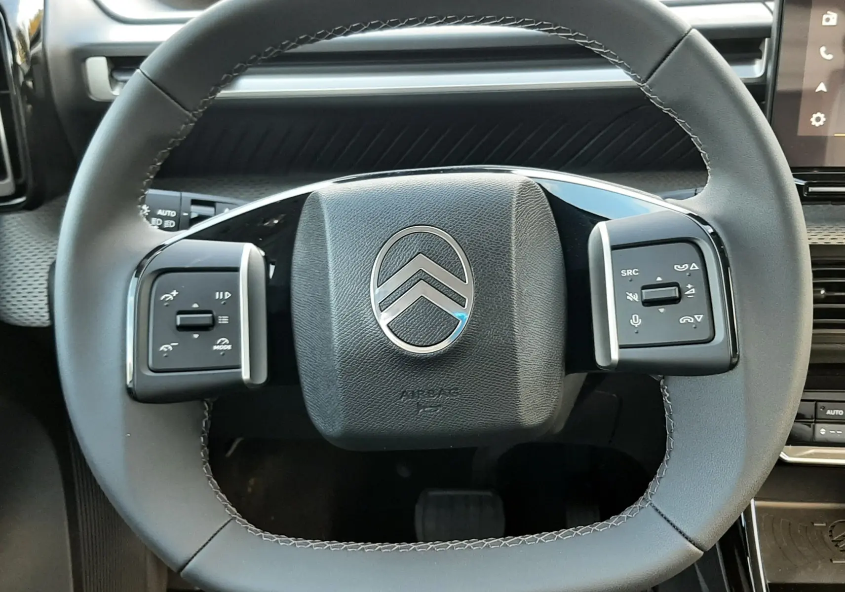 Vue rapprochée du volant noir de la Citroën C3 Aircross 2026, mettant en valeur les commandes intégrées et le logo central.