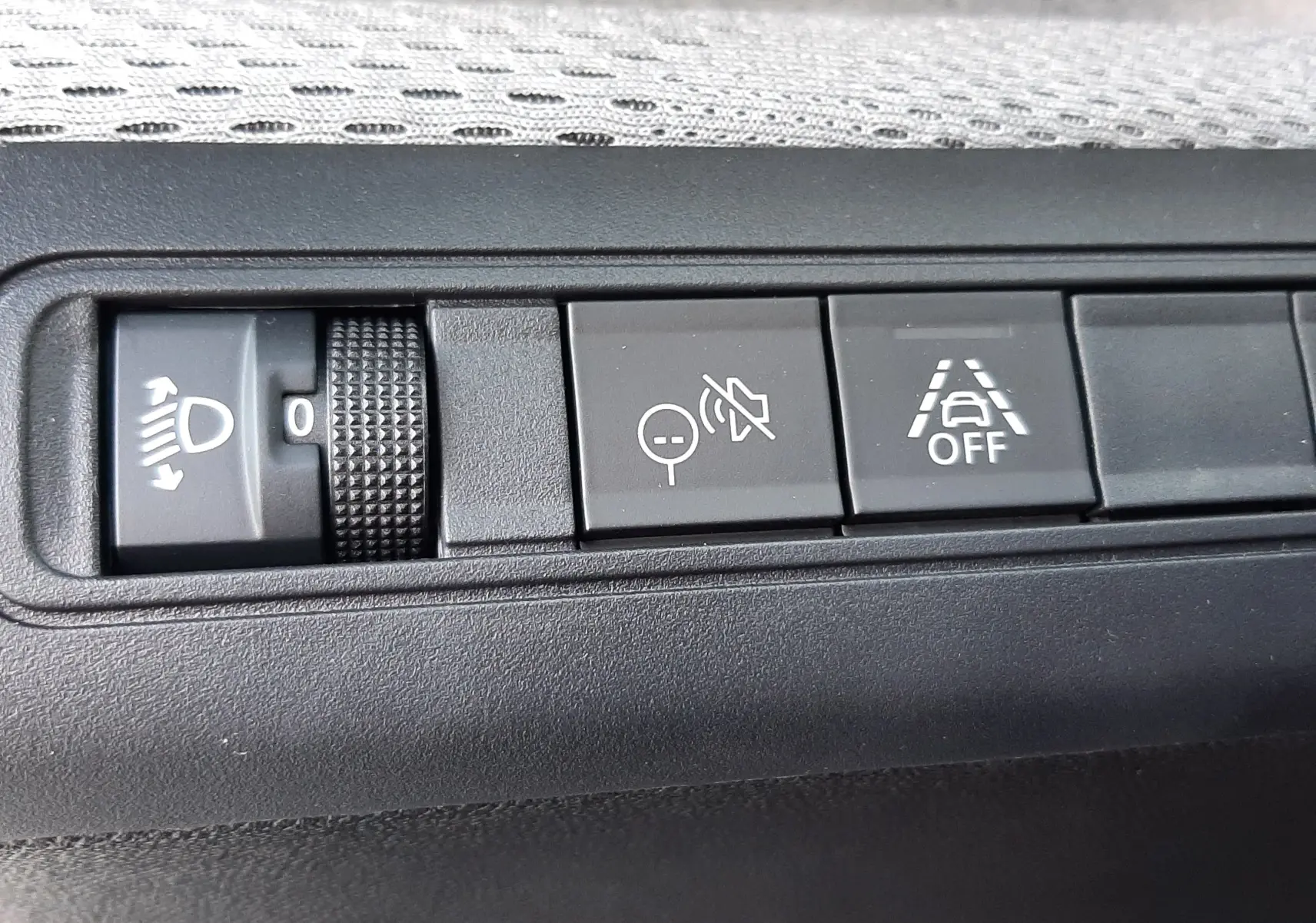 Gros plan sur les commandes intérieures du Citroën C3 Aircross 2026, avec réglage des phares et boutons d'assistance à la conduite.