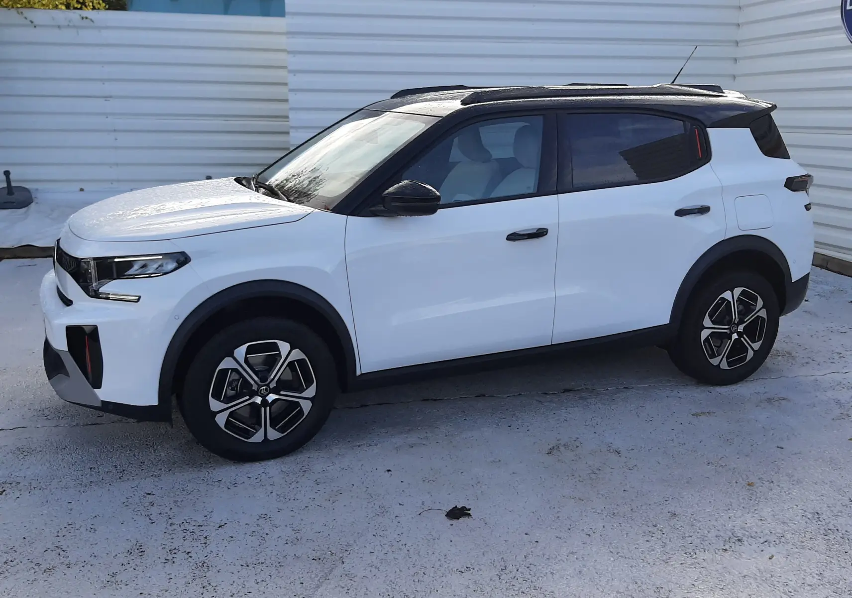 Citroën C3 Aircross blanc avec toit noir, vue de profil côté gauche, jantes stylisées et détails noirs contrastants.