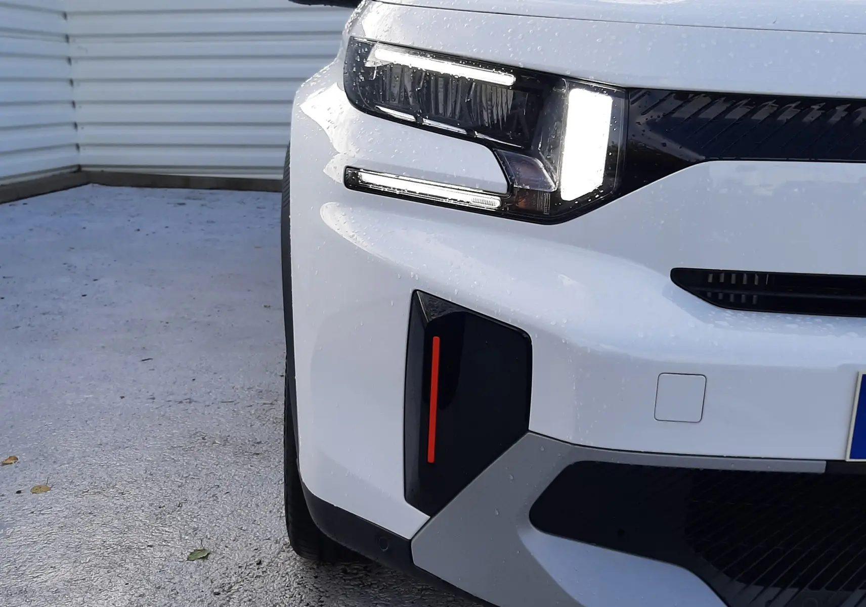 Gros plan sur l'avant gauche du Citroën C3 Aircross blanc avec toit noir, mettant en valeur son phare LED distinctif.