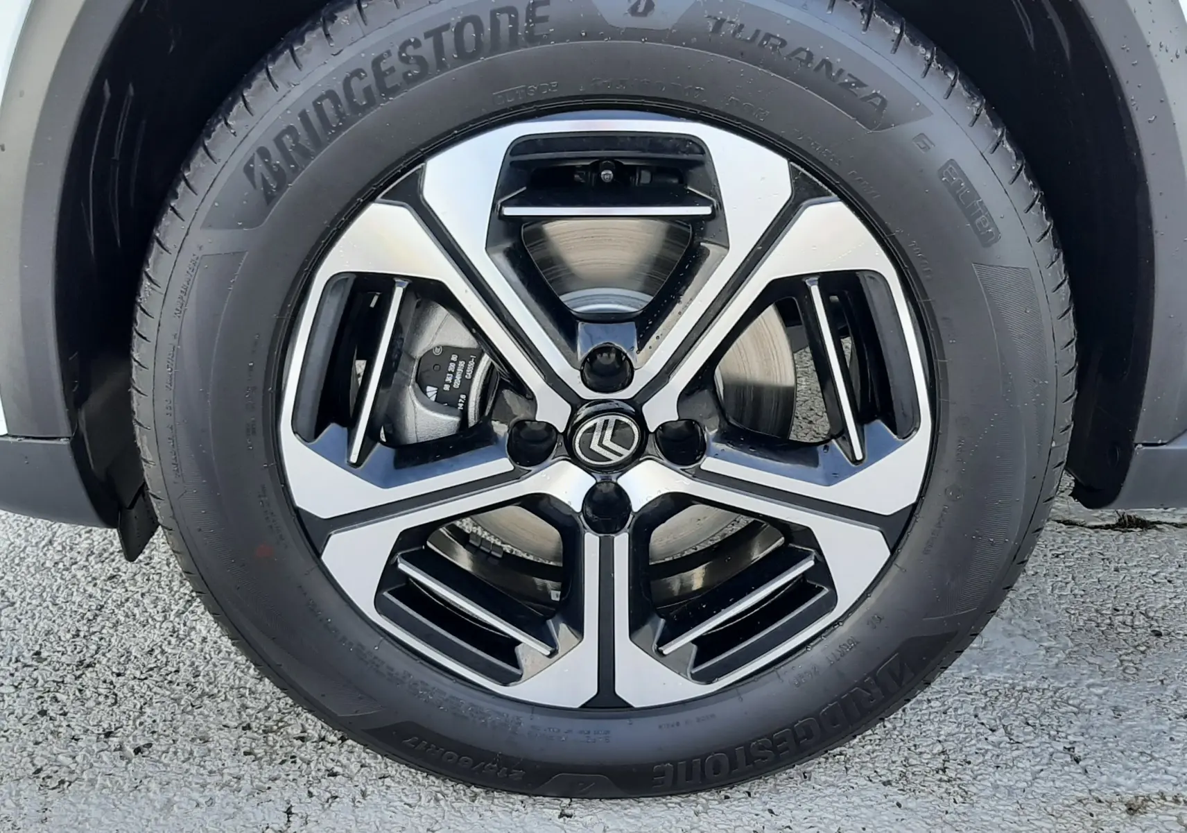 Gros plan sur la roue avant droite du Citroën C3 Aircross blanc avec jante alliage bicolore et pneu Bridgestone.