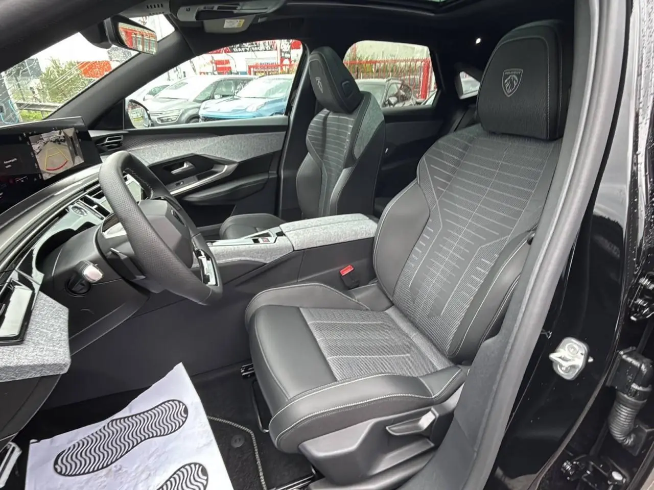 Vue intérieure côté conducteur du Peugeot 3008 gris titane, mettant en valeur les sièges Alcantara embossés et le tableau de bord moderne.