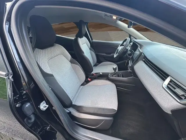 Intérieur de la Renault Clio V 1.5 Blue dCi 100 Evolution 2025, vue côté gauche, sièges tissu gris noir et tableau de bord épuré.