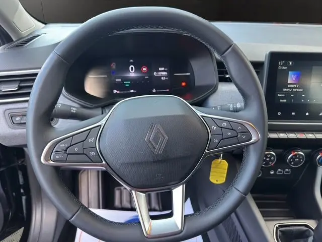 Volant noir de Renault Clio V 2025 vu de face, avec commandes intégrées et tableau de bord numérique allumé.