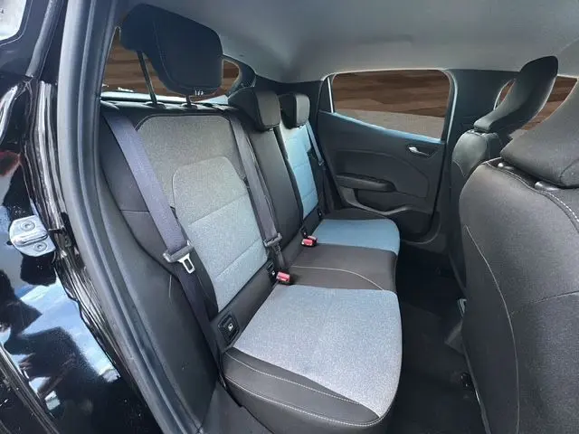 Vue intérieure arrière gauche sur les sièges tissu gris et noir de la Renault Clio V 1.5 Blue dCi 100 Evolution 2025 noire.