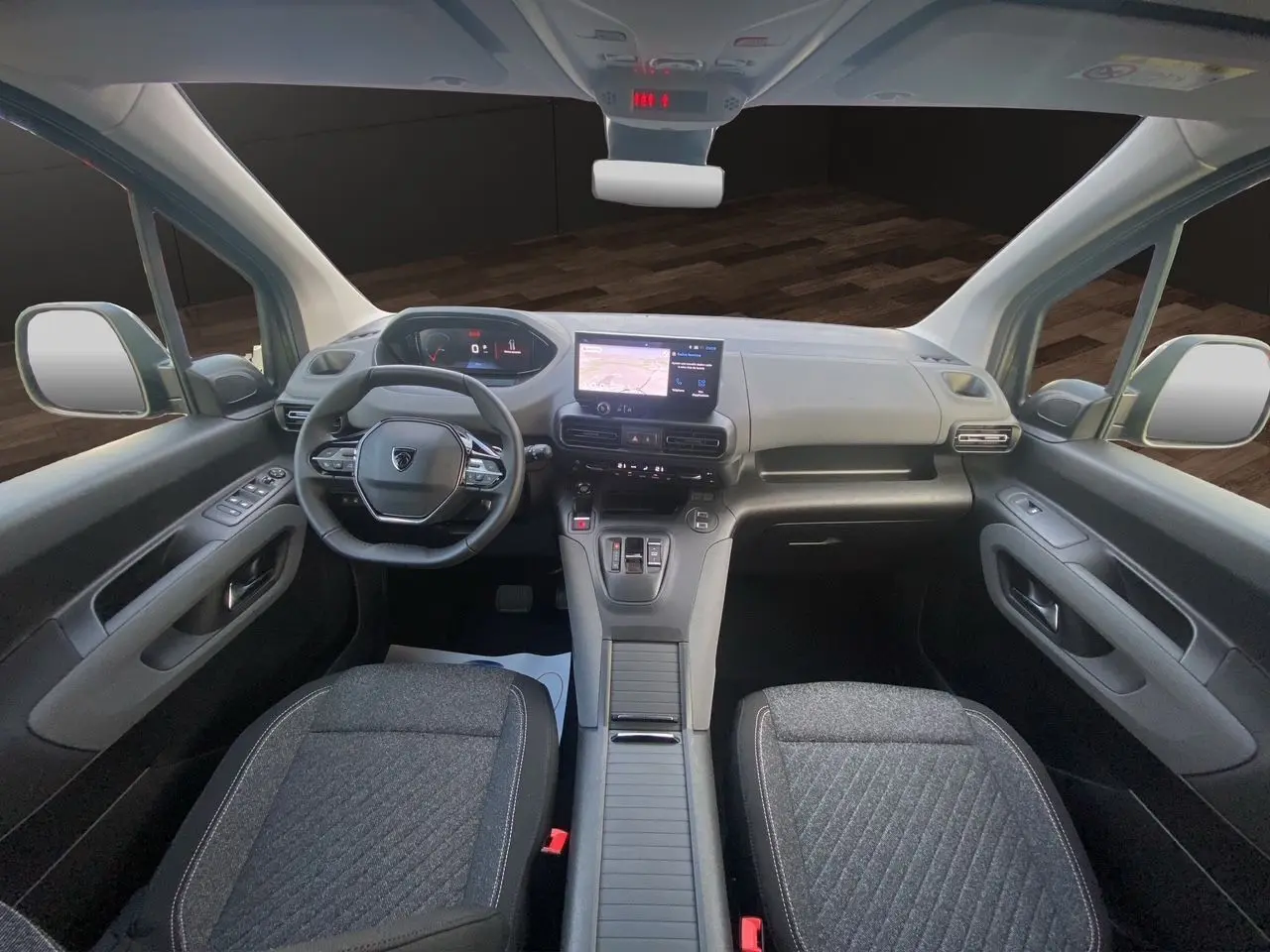 Vue intérieure avant du Peugeot Rifter 2025 avec tableau de bord gris noir et sièges tissu gris foncé.