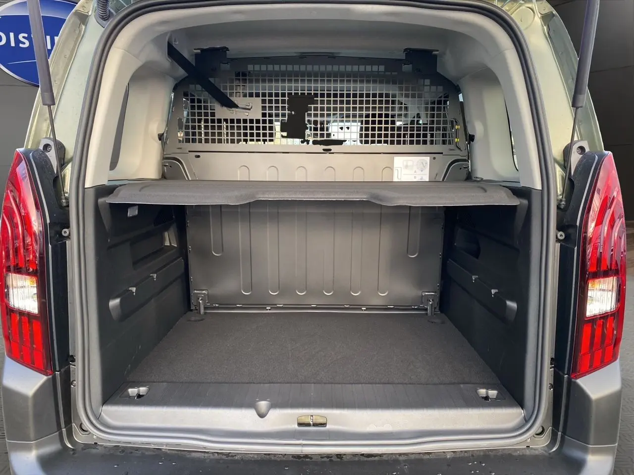 Vue arrière du Peugeot Rifter 1.5 BlueHDi vert Sirkka, coffre ouvert avec cloison métallique de séparation visible.