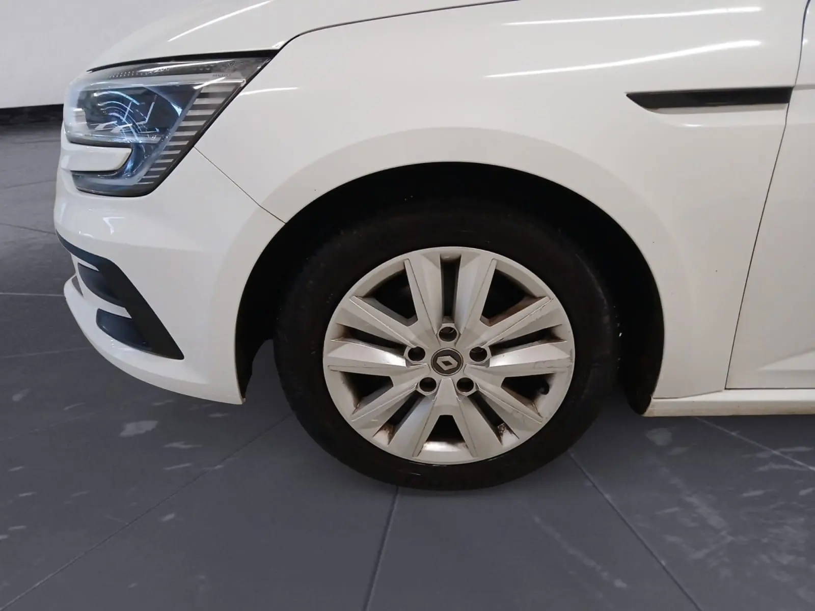 Gros plan sur la roue avant gauche et le phare d’une Renault Mégane IV blanche, version PH2 BlueDCI 115 Zen de 2020.