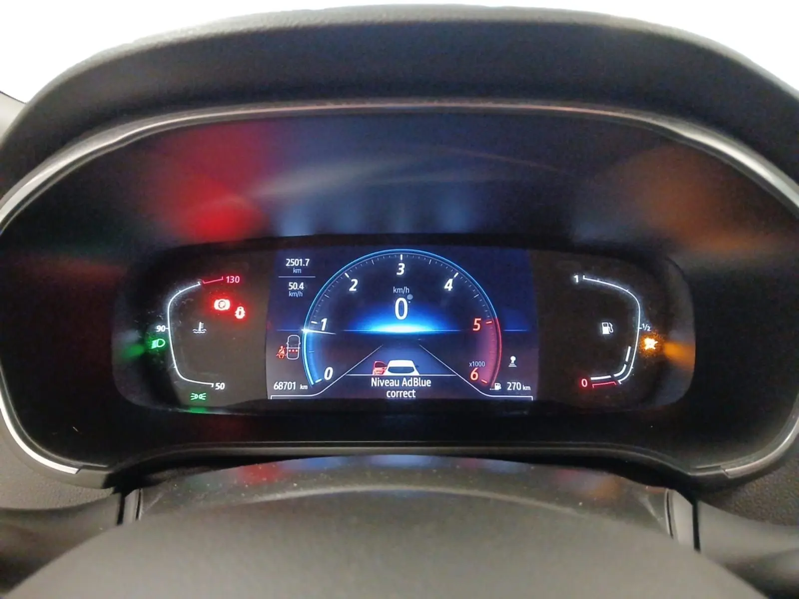 Vue rapprochée du tableau de bord numérique de la Renault Mégane IV blanche, affichant les compteurs et alertes.