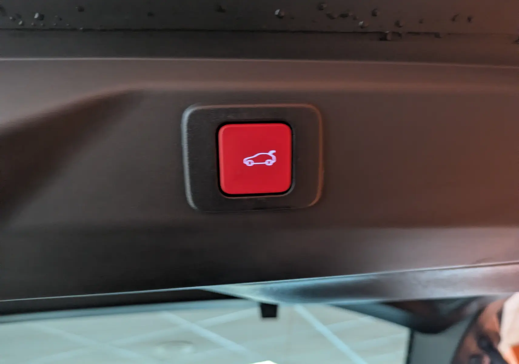 Bouton rouge de fermeture électrique du hayon sur le bord intérieur du coffre du Peugeot 3008 gris titanium.