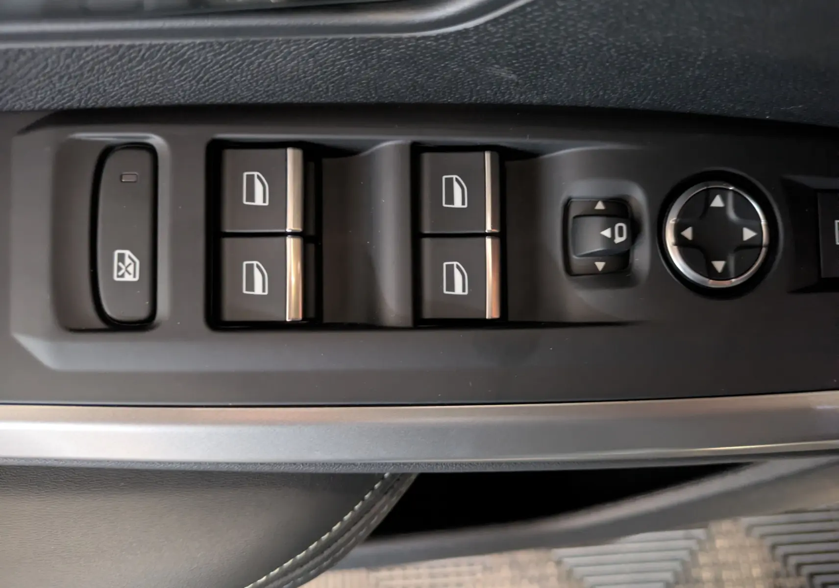 Gros plan sur les commandes de lève-vitres et réglage des rétroviseurs côté conducteur du Peugeot 3008 gris titanium.