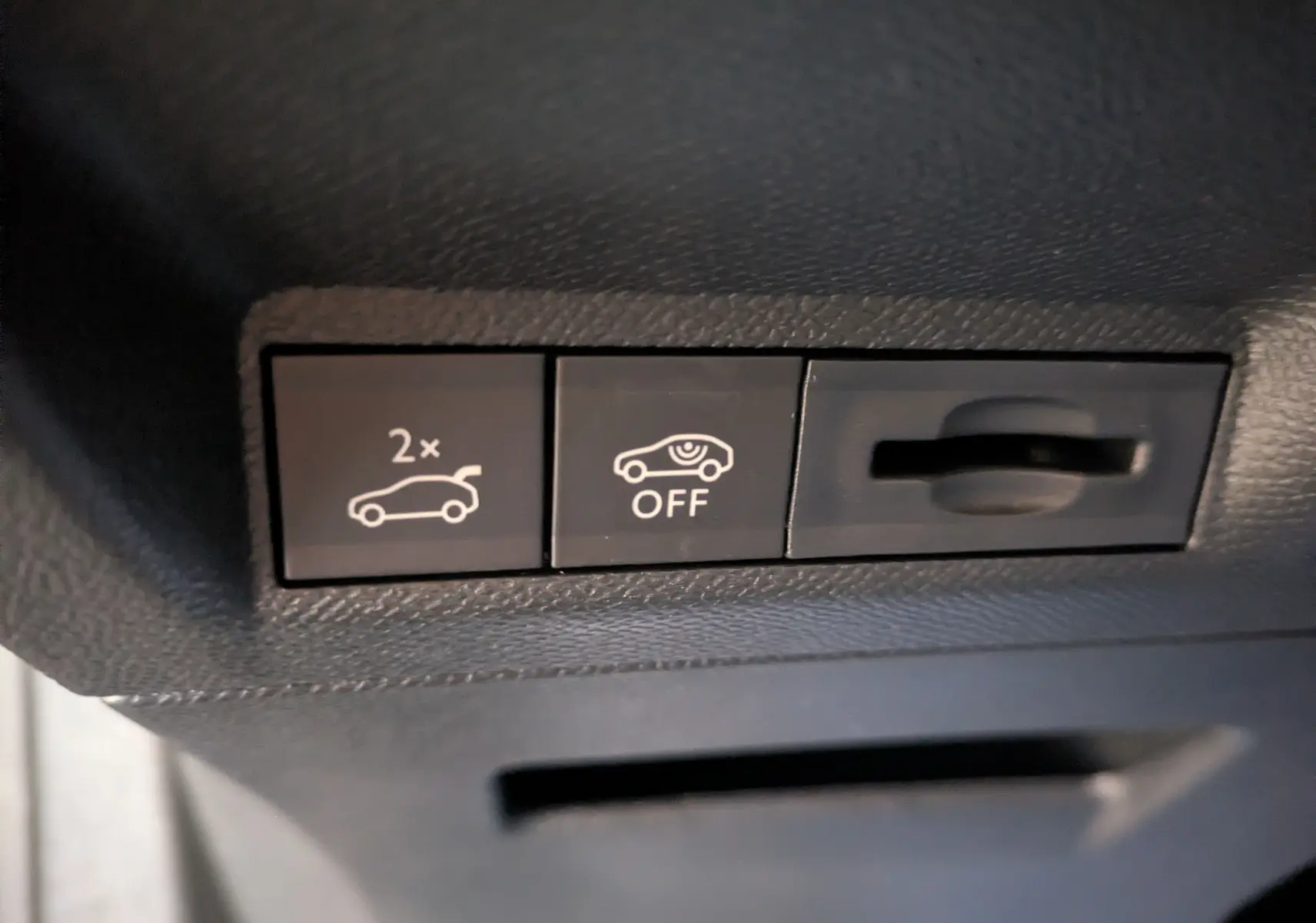 Détail intérieur montrant les boutons de commande d'ouverture du hayon et de désactivation d'alerte sur Peugeot 3008 gris titanium.