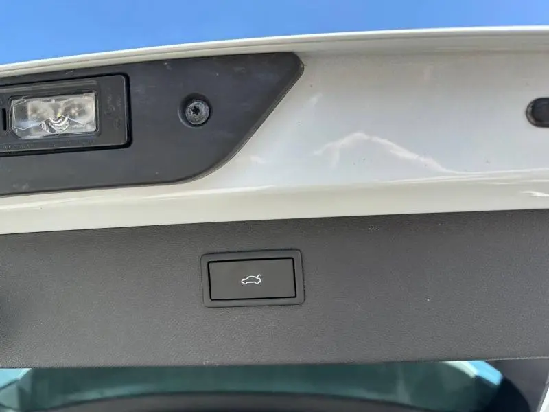 Gros plan sur le bouton d'ouverture électrique du coffre, intérieur de la malle arrière d'une CUPRA Formentor noir Minuit.