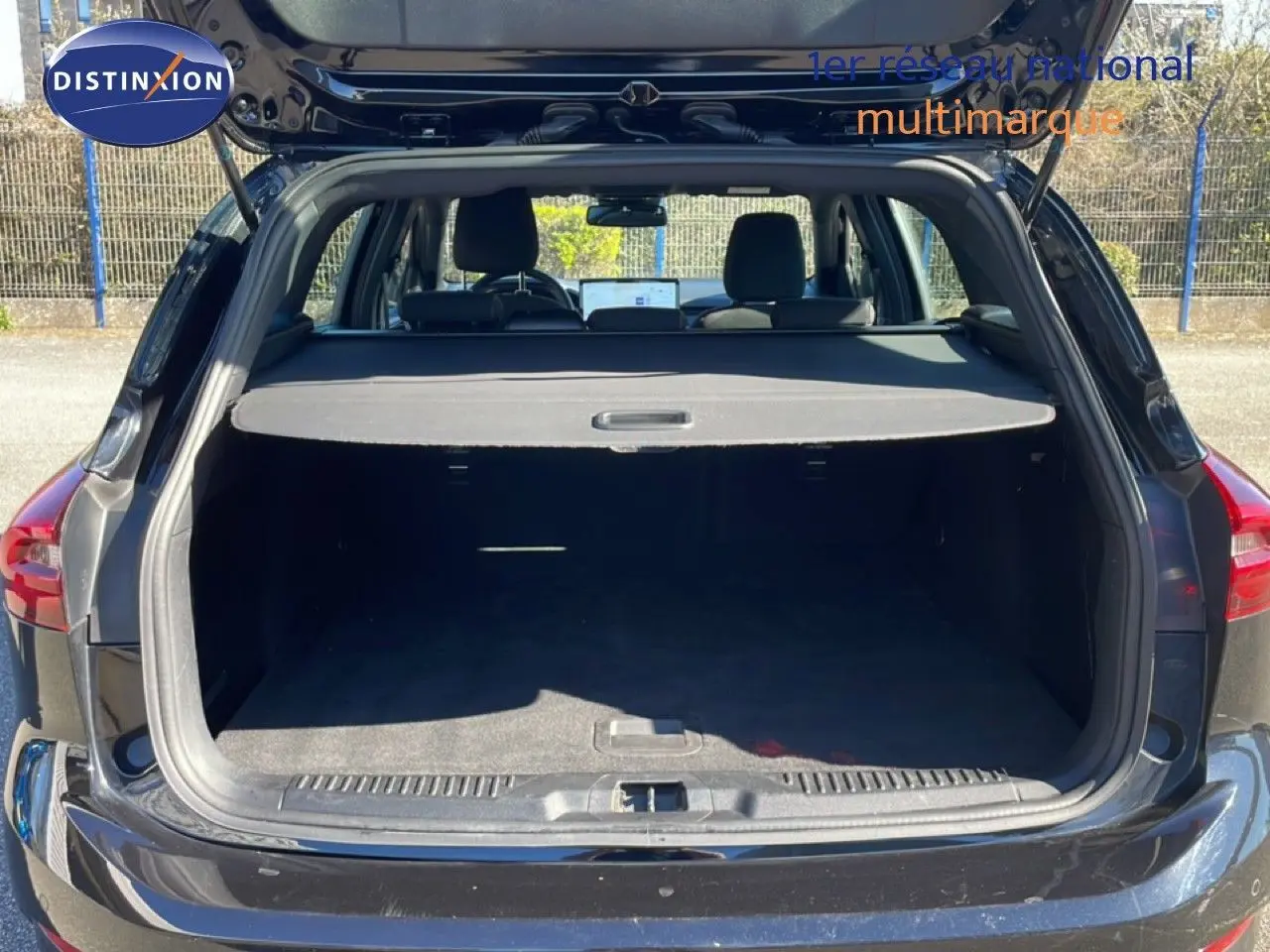 Vue arrière du coffre ouvert d'une Ford Focus SW 1.5 EcoBlue noire, mettant en valeur l'espace de chargement et la tablette cache-bagages.