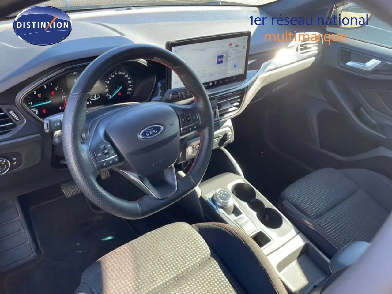 Vue intérieure côté conducteur de la Ford Focus SW noire, avec volant cuir, écran tactile et console centrale moderne.