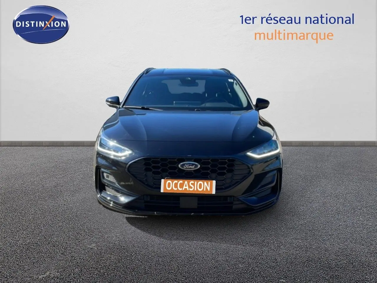 Vue frontale d'une Ford Focus SW noire Agate Metal 2024 avec calandre hexagonale et phares LED allumés.