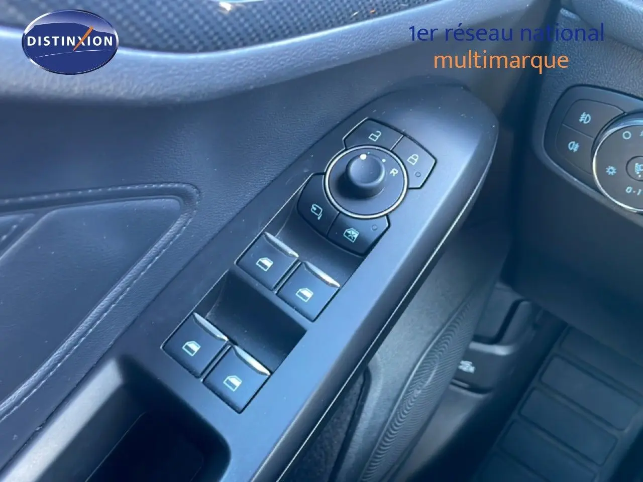 Gros plan sur les commandes de lève-vitres et rétroviseurs côté conducteur d'une Ford Focus SW noire 2024.