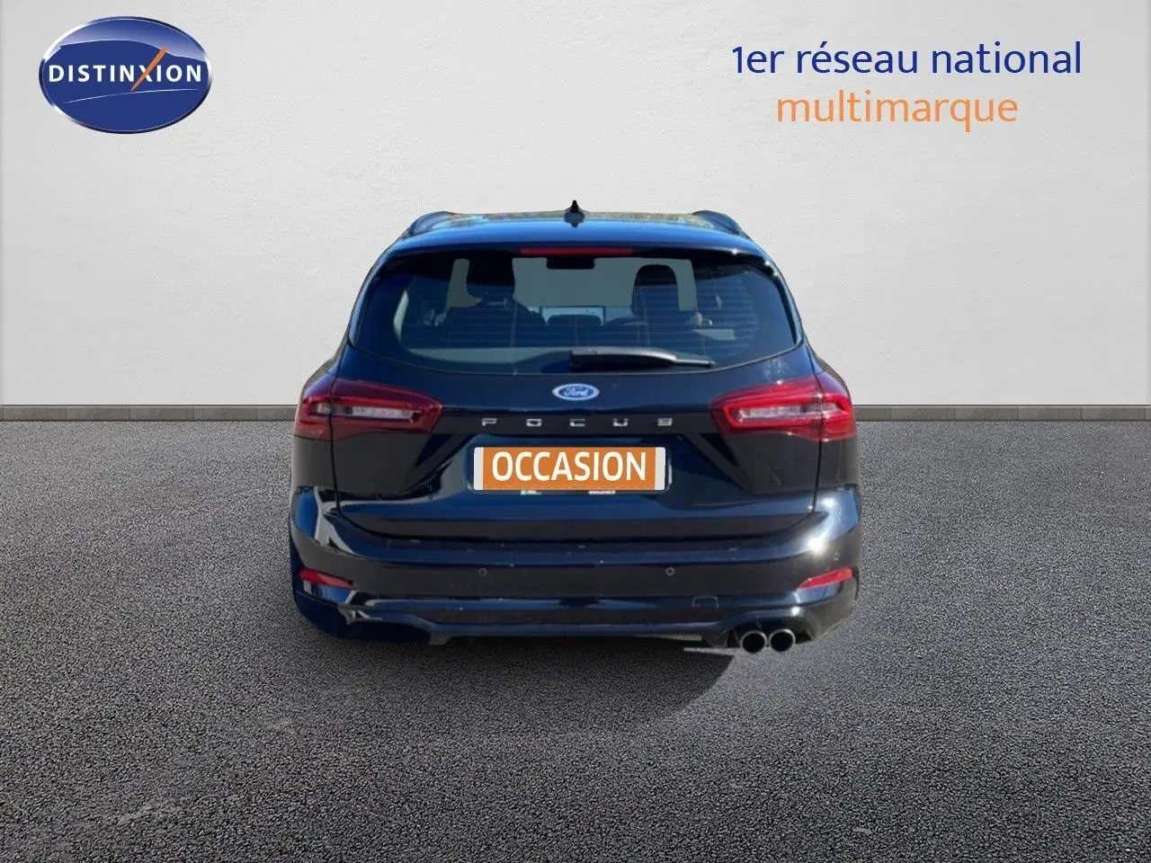 Vue arrière d'une Ford Focus SW noire Agate Metal avec double sortie d'échappement et logo Ford visible.