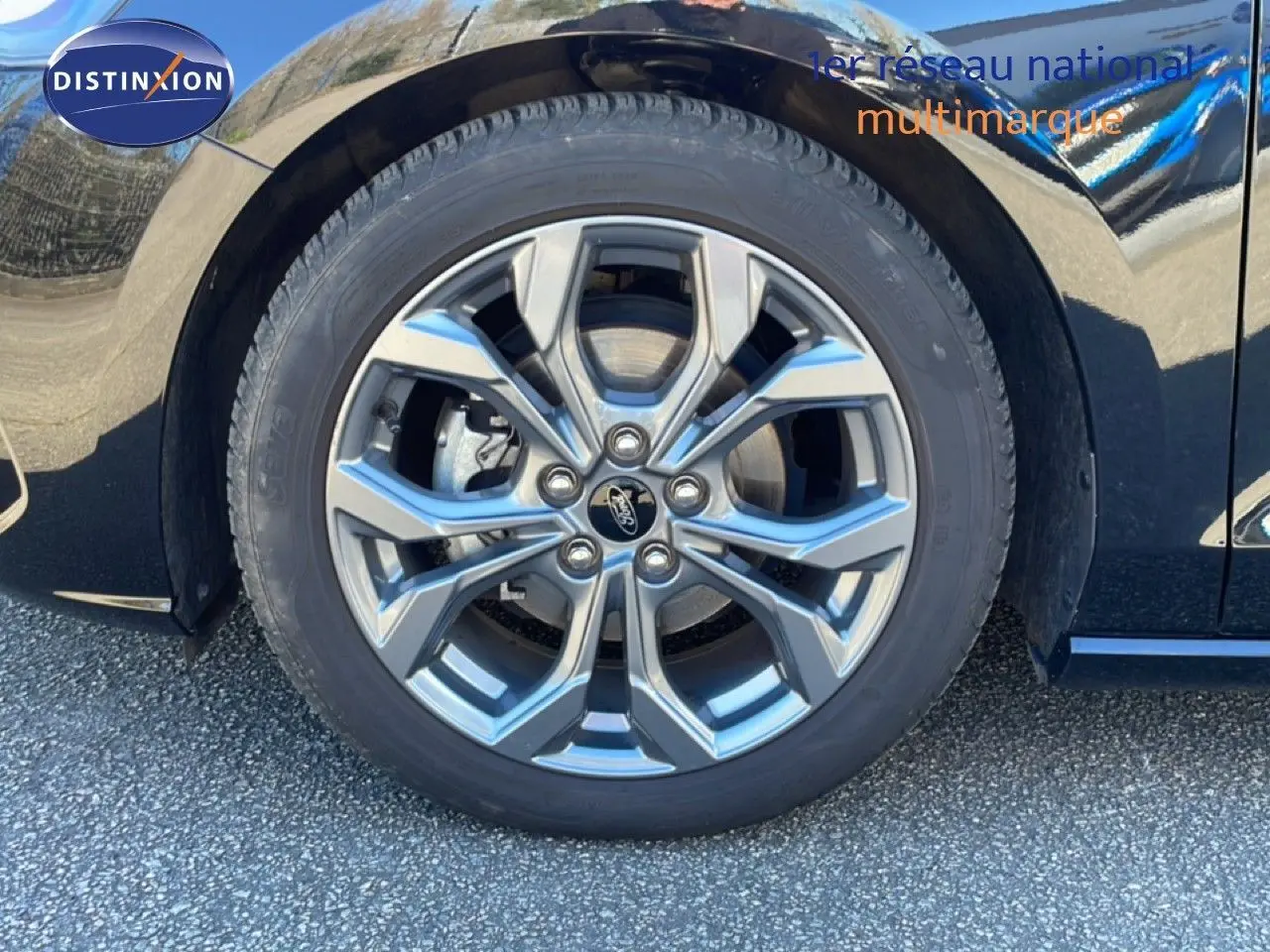 Gros plan sur la roue avant droite de la Ford Focus SW noire, mettant en valeur la jante alliage au design moderne.