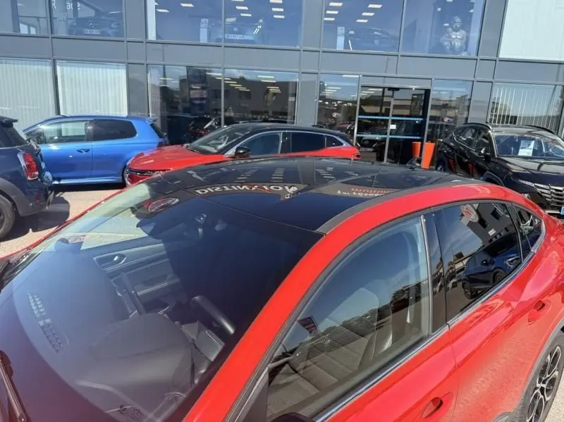 Renault Arkana rouge flamme vue 3/4 arrière droit, toit panoramique noir et vitres teintées visibles.