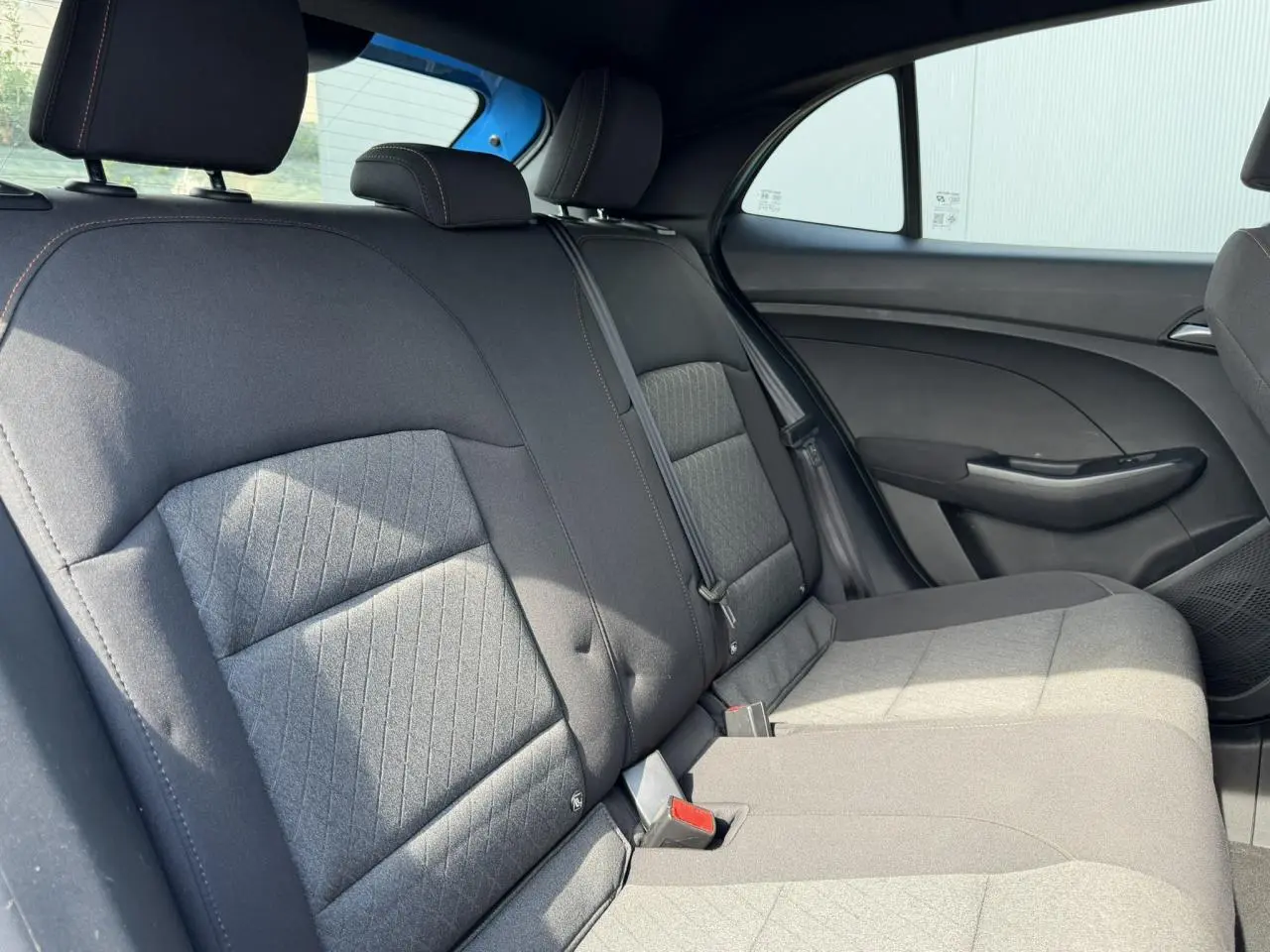 Vue intérieure des sièges arrière en tissu noir de la MG3 1.5 Hybrid+ 195 Comfort, avec ceinture et porte latéral côté droit.