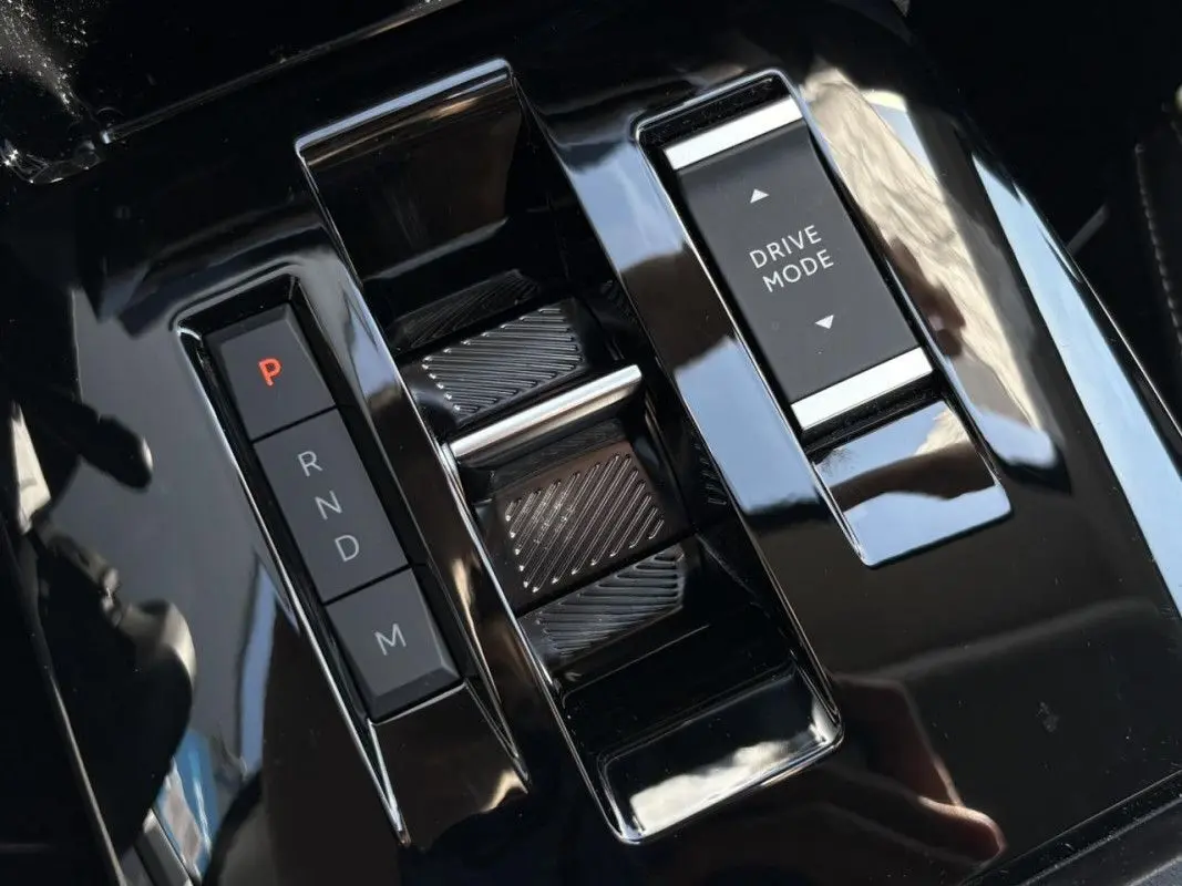 Gros plan sur la console centrale noire brillante du Citroën C4 Hybrid 145 CH avec sélecteur de vitesses et bouton Drive Mode.