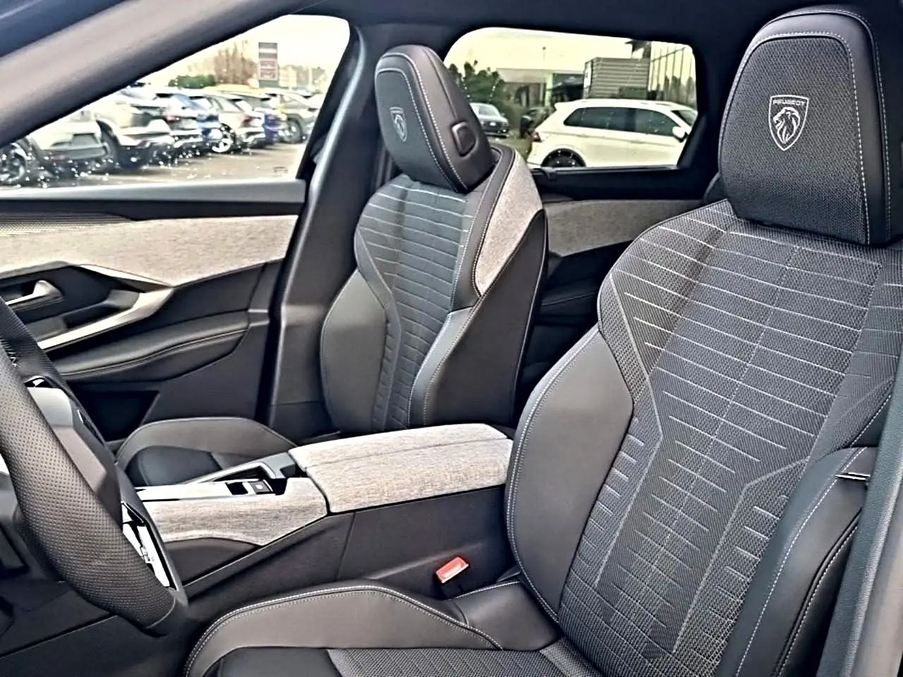 Vue intérieure côté conducteur du Peugeot 5008 Hybrid 145 GT avec sièges tissu noir et gris et logo Peugeot brodé.