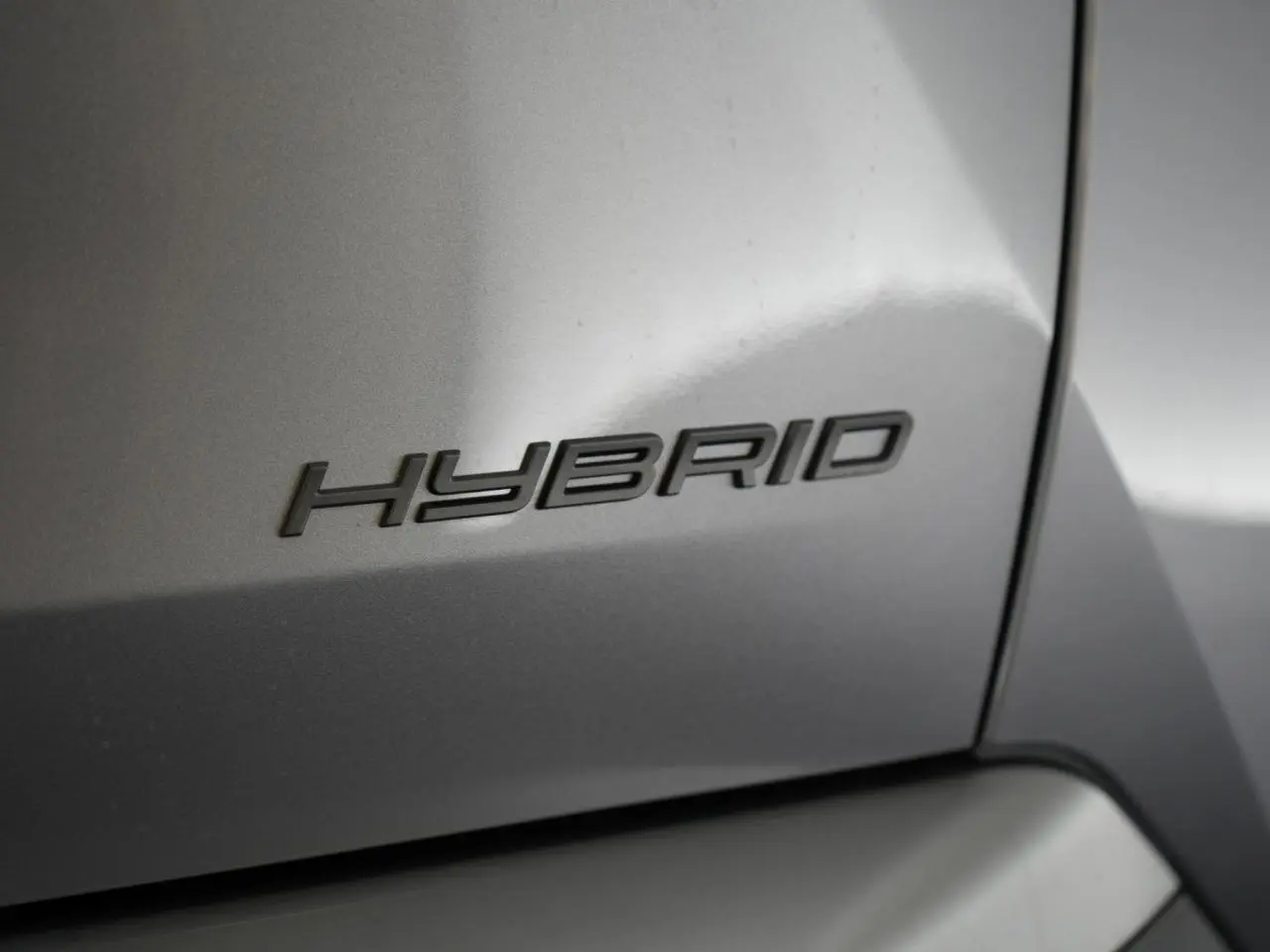 Gros plan sur l’inscription « Hybrid » en relief sur la carrosserie gris Artense d’un Peugeot 3008.