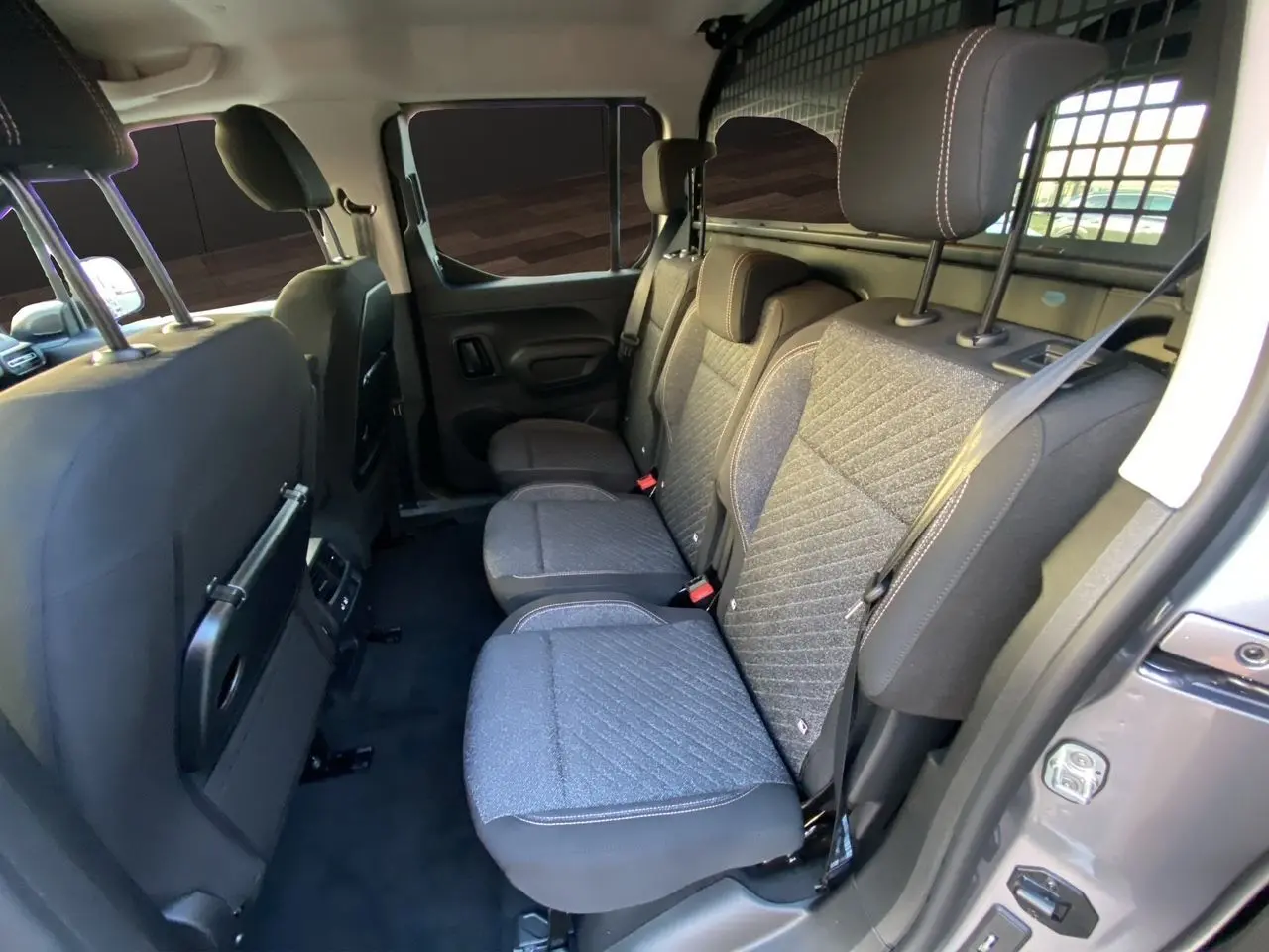 Vue intérieure côté droit sur les sièges arrière gris tissu du Peugeot Rifter 2025 avec cloison métallique de séparation.