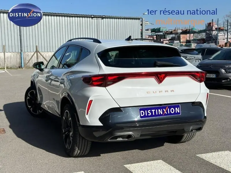 Vue 3/4 arrière droite d'un CUPRA Formentor blanc Nevada métallisé avec feux arrière reliés et double sortie d'échappement.