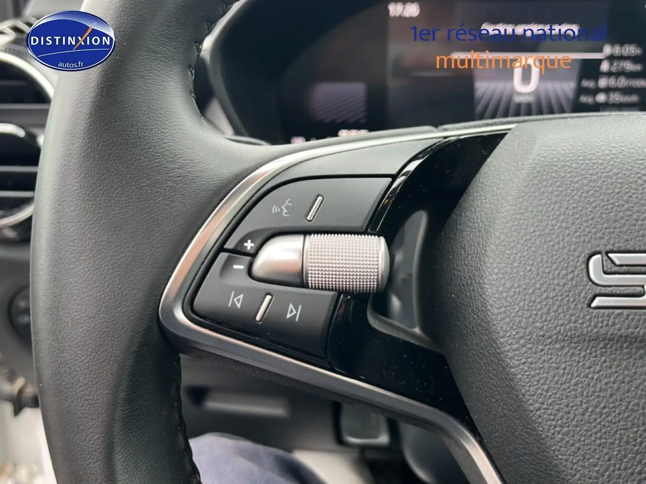 Gros plan sur les commandes gauche du volant cuir multifonction d’une Skoda Fabia blanche 2025, avec molette argentée.