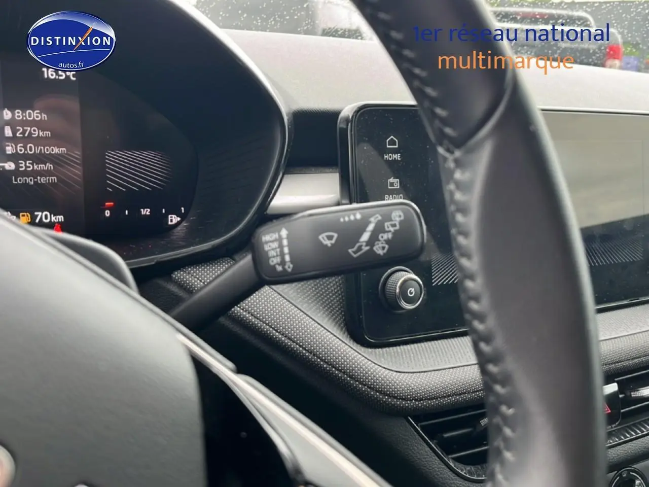 Vue rapprochée du tableau de bord et du volant cuir noir d'une Skoda Fabia blanche, avec écran tactile et commandes au volant.