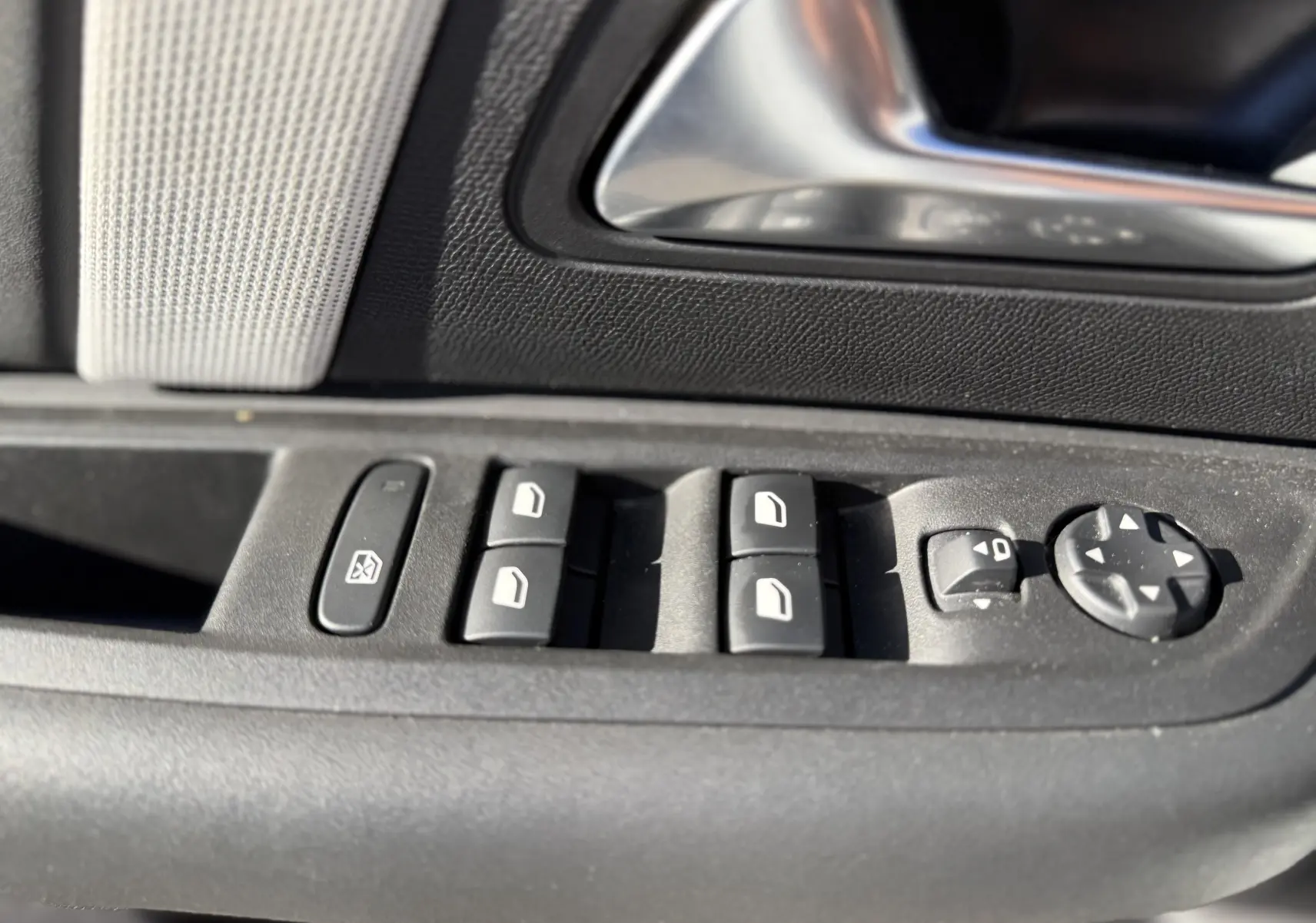 Gros plan sur les commandes de lève-vitres et rétroviseurs côté gauche d’une Citroën C4 blanche, intérieur noir.