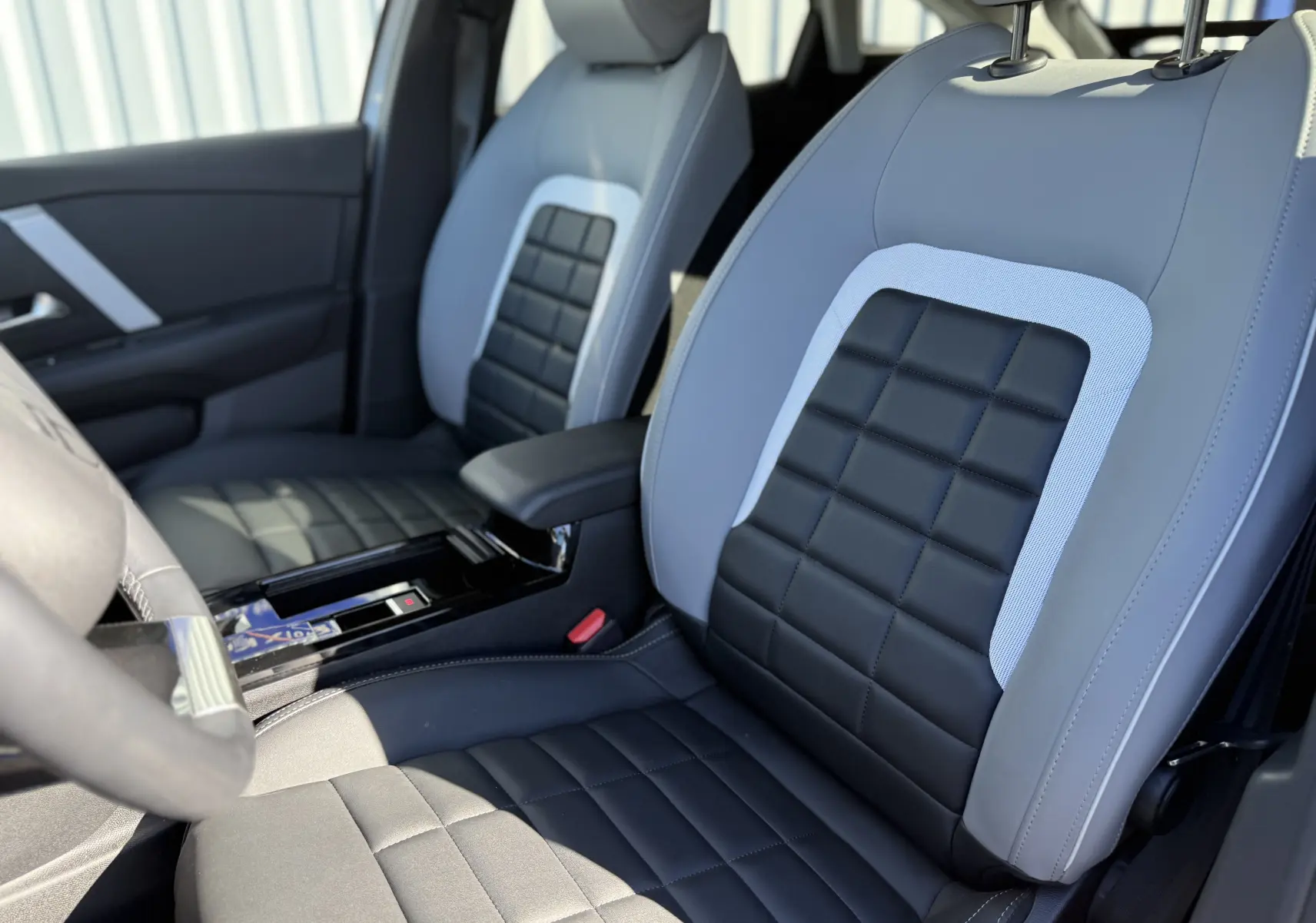 Vue rapprochée des sièges avant bi-ton gris clair et noir en cuir de la Citroën C4 Hybrid 2025.