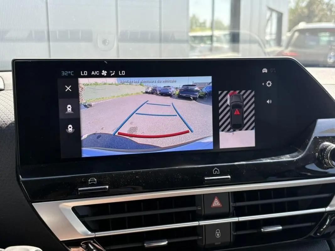 Coffre ouvert vu de l'arrière d'une Citroën C4 Hybrid 145 ch blanc Okenite, espace de chargement vide et propre.
