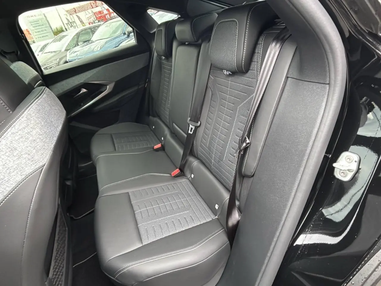 Vue intérieure côté droit des sièges arrière en cuir noir et tissu gris du Peugeot 3008 noir Perla 2026.