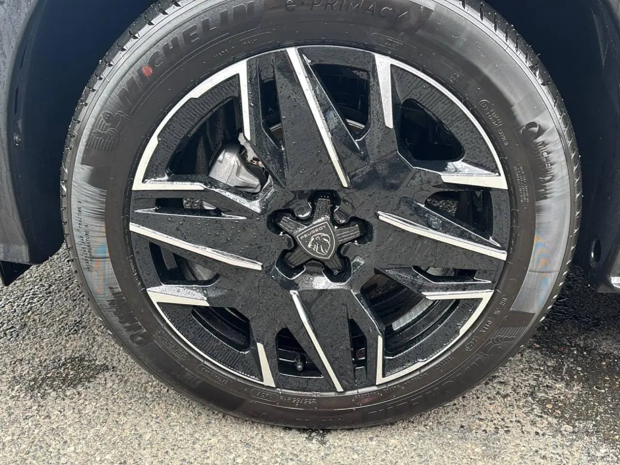 Gros plan sur la jante alliage noire et diamantée 19'' avec logo Peugeot, sur fond de carrosserie noir perla.