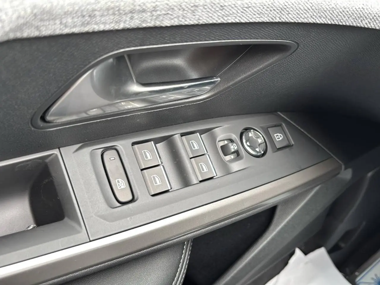 Gros plan sur la commande des vitres et rétroviseurs côté conducteur d’un Peugeot 3008 noir Perla, intérieur noir.