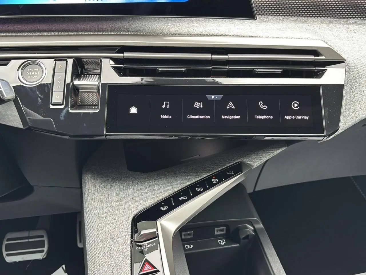 Vue rapprochée de la console centrale du Peugeot 3008 2026, écran tactile et commandes modernes sur fond tissu gris.
