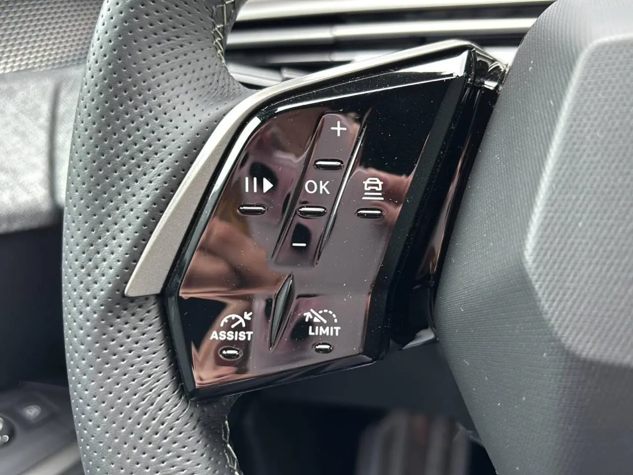 Gros plan sur les commandes noires du volant du Peugeot 3008 2026, avec boutons d'assistance et limitation de vitesse.