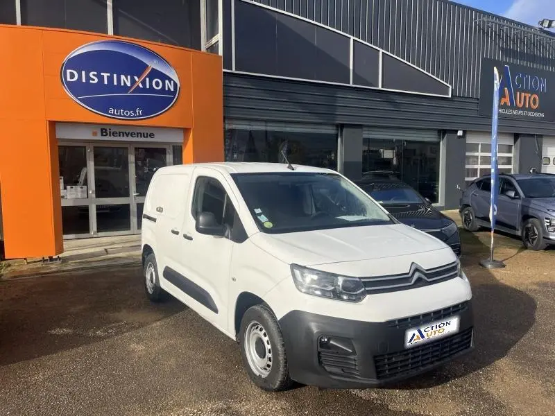 Citroën Berlingo Fourgon blanc Banquise en 3/4 avant droit devant un garage avec enseigne orange.