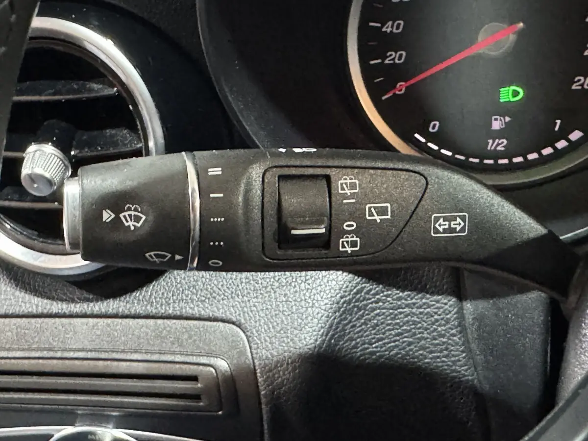 Gros plan sur la commande d’essuie-glace à gauche du volant dans le tableau de bord noir du Mercedes Classe C Break C 200 d Business Line.