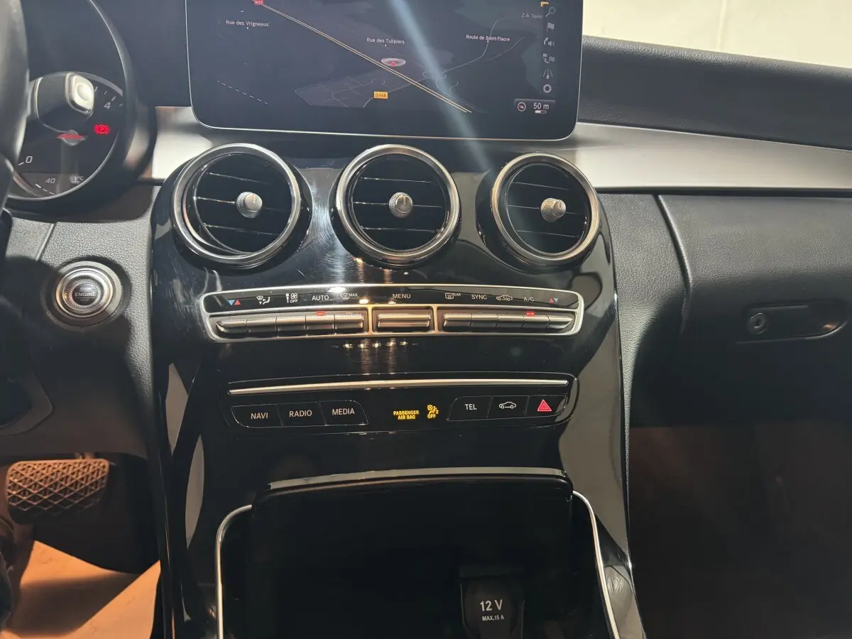 Vue rapprochée du tableau de bord noir brillant de la Mercedes Classe C Break C 200 d avec écran de navigation et commandes climatisation.