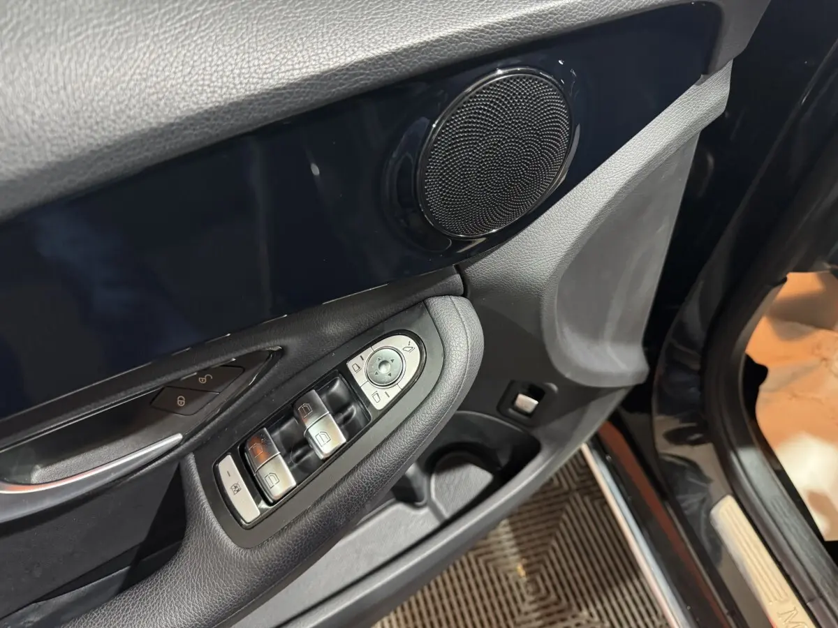 Détail de la porte côté conducteur d’un Mercedes Classe C Break noir, avec commandes des vitres et haut-parleur intégré.
